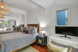Relax in this serene bedroom with a large bed, bedside table, and mounted television.