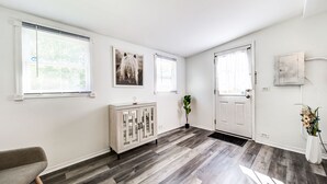 Ein heller, moderner Flur mit Holzboden, einer weißen Tür und einem Schrank mit Glastüren.