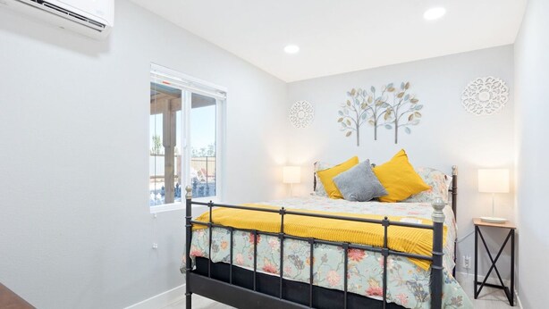 A bedroom with a bed, bedside lamps, decorative wall art, and a window. - Mystic Views: Pool, Hot Tub, Game Room & Fire Pit! (Twentynine Palms)