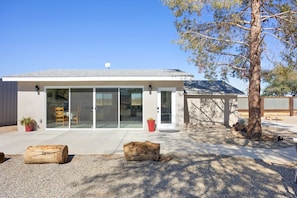 A modern house with a patio, a large tree, and a wooden log. - Mystic Views: Pool, Hot Tub, Game Room & Fire Pit! (Twentynine Palms)