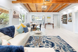 A spacious living room with a white sofa, a glass coffee table, and a blue patterned rug. - Mystic Views: Pool, Hot Tub, Game Room & Fire Pit! (Twentynine Palms)
