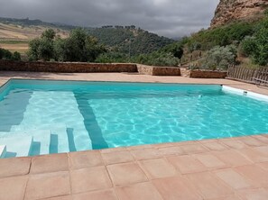 A rectangular swimming pool with clear blue water, surrounded by stone walls and a stone deck. - Hotel La Mirada de Ronda  (Ronda)