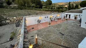 A courtyard with stone flooring, outdoor seating, and a white building with multiple doors. - Hotel La Mirada de Ronda  (Ronda)