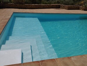 A rectangular swimming pool with clear blue water, surrounded by a stone wall and a tiled deck. - Hotel La Mirada de Ronda  (Ronda)