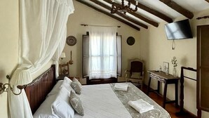 A bedroom with a bed, a TV, a desk, and a window with curtains. - Hotel La Mirada de Ronda  (Ronda)