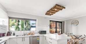 Une cuisine moderne avec des meubles blancs, un lave-vaisselle intégré et une grande fenêtre offrant une vue sur la verdure environnante.