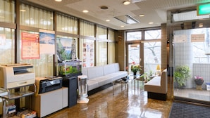 A reception area with a sofa, a fish tank, a printer, and a desk with a computer. - Business Ryokan Hotel Yukimiso (Toyama)