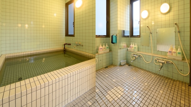 A bathroom with a large bathtub, a shower area, and a mirror. - Business Ryokan Hotel Yukimiso (Toyama)