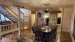 Interior de madera con una mesa de comedor, sillas, una escalera y una zona de cocina.