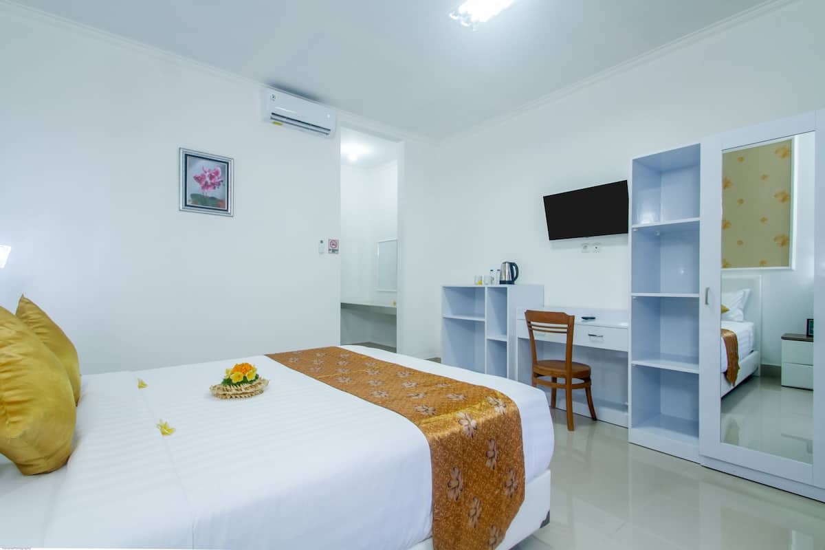 A hotel room with a bed, a desk, a chair, a wardrobe, and a television on the wall.