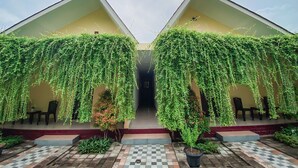 A building with two covered areas, each with hanging greenery and a checkered tile floor. - Kesari Penida by Mahaprana Home (Penida Island)