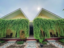 Un edificio con dos zonas cubiertas, cada una decorada con plantas colgantes y un suelo de baldosas de cuadros.