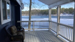 A covered porch with a view of a frozen lake and houses in the background. - Looking to get away this fall?  Come enjoy the Lake House! (Gaylord)
