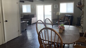 A spacious living area with a dining table, wooden chairs, a sofa, and a balcony. - Looking to get away this fall?  Come enjoy the Lake House! (Gaylord)