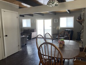 Amplia sala de estar con mesa de comedor, sillas de madera, un sofá y un balcón.