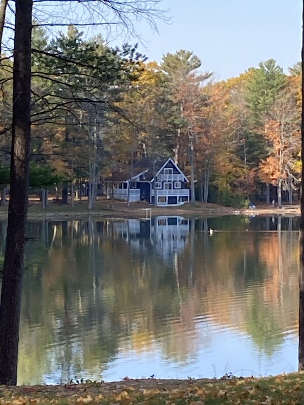 A house by a calm lake surrounded by trees.