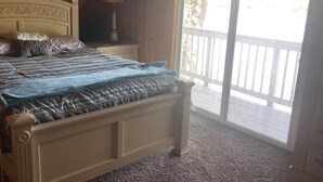 A bedroom with a bed, a nightstand, a lamp, and a view of a balcony. - Looking to get away this fall?  Come enjoy the Lake House! (Gaylord)