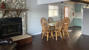 A dining area with a stone fireplace, wooden chairs, and a table with potted plants. - Looking to get away this fall?  Come enjoy the Lake House! (Gaylord)