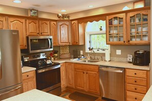 A kitchen with wooden cabinets, a stainless steel refrigerator, a microwave, a stove, and a coffee maker.