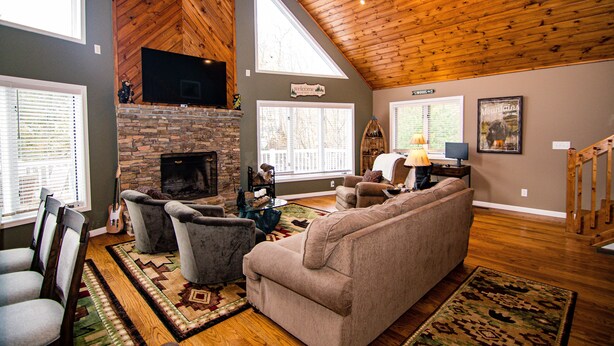 Un salón amplio con chimenea, asientos cómodos y ventanas grandes.
