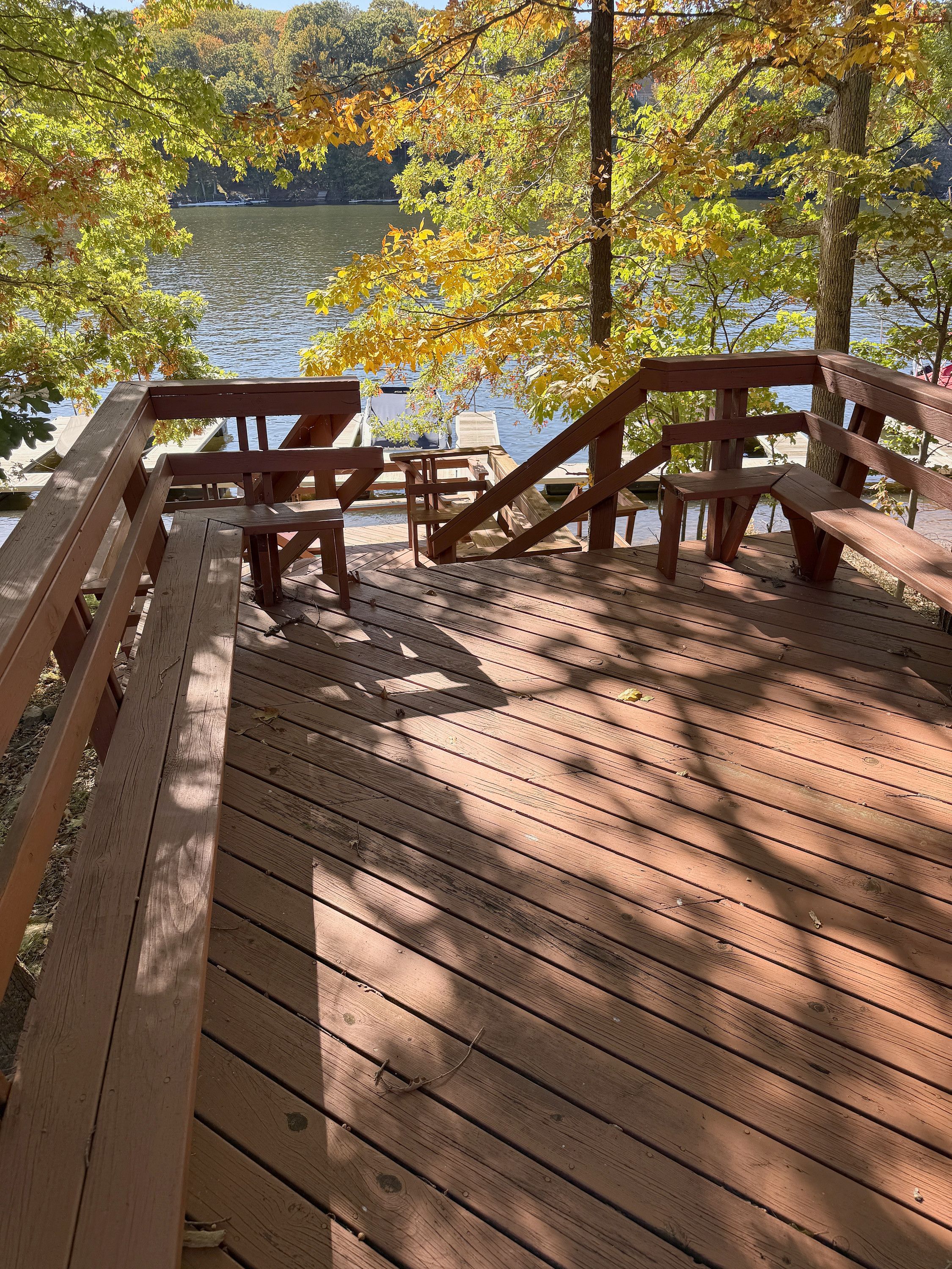 A wooden deck with benches overlooking a lake.