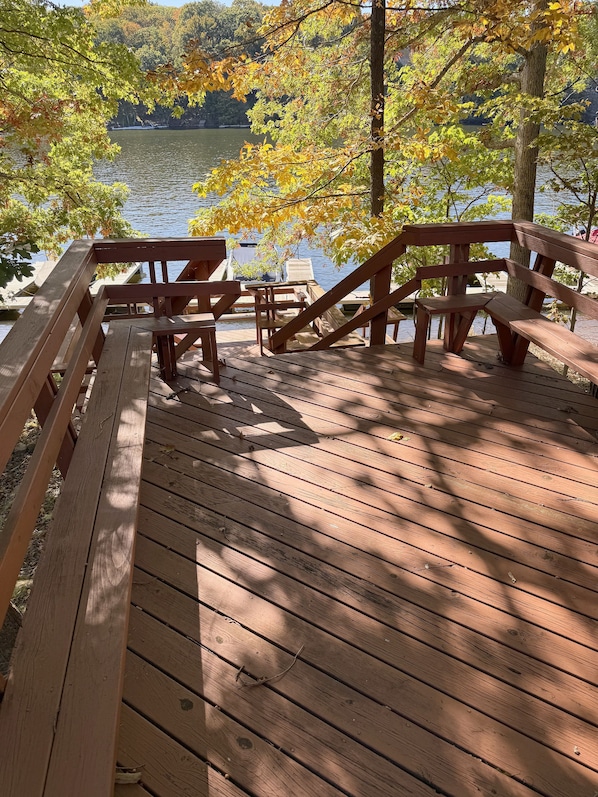 A wooden deck with benches overlooking a lake.