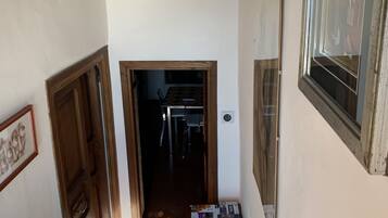 A narrow stairway leading to a room with a wooden ceiling, a window, and a door.