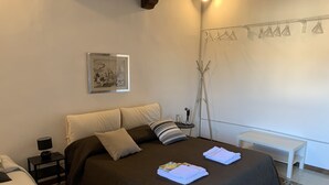A neatly arranged bedroom with a large bed, a bedside table, a small desk, and a wall-mounted drying rack. - Porta Conca (Rieti)