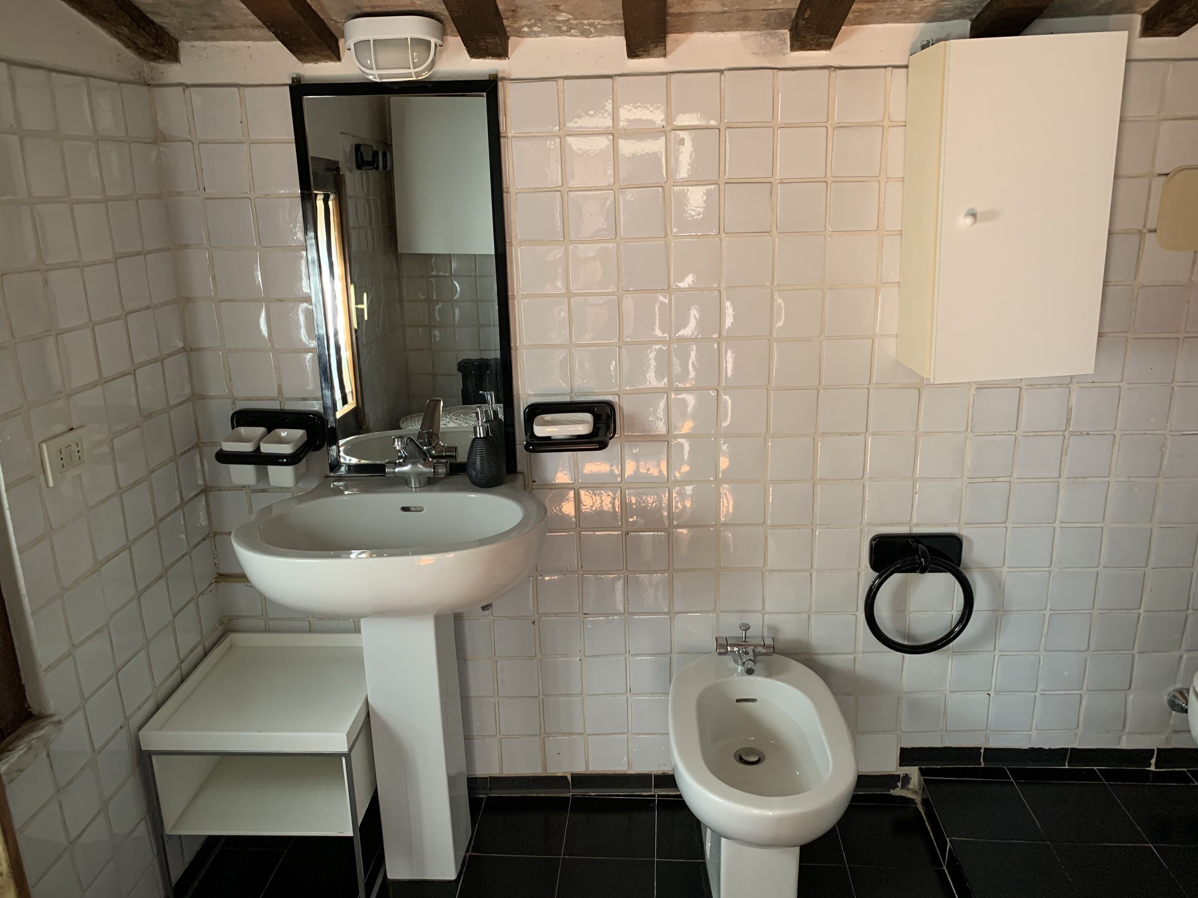 Ein Badezimmer mit Waschbecken, Spiegel, Bidet und weißem Schrank.