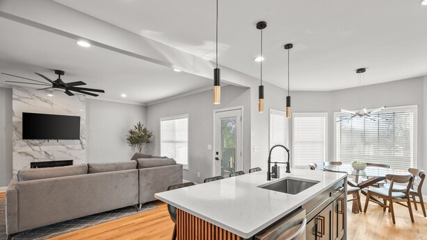 A modern kitchen with a central island, wooden flooring, and a dining area with a table and chairs. - NEW - High End Luxury Home in the Heart of Atlanta (Atlanta)