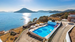 Una piscina con vistas al mar y a las montañas, un puente a lo lejos, y un edificio con un balcón.