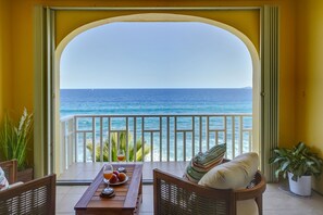 A balcony with a view of the ocean, a table with drinks and fruit, and wicker furniture. - Gorgeous Ocean View!!! Condo in Gated Community!!! (Christiansted)