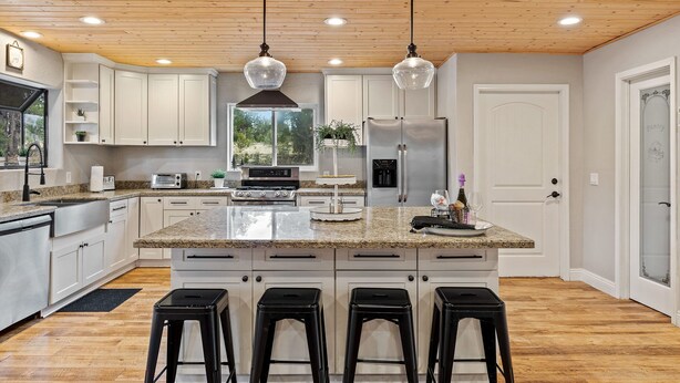 A modern kitchen with white cabinets, granite countertops, a central island with bar stools, stainless steel appliances, and pendant lighting. - 4 Bedrooms, Sleeps 16, Hot Tub, Games, Tesla Charger, Smart TV's,  MORE! (Heber)