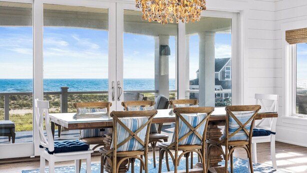 Ein Essbereich mit Meerblick, ausgestattet mit einem Tisch, Stühlen und einer Chandelier.