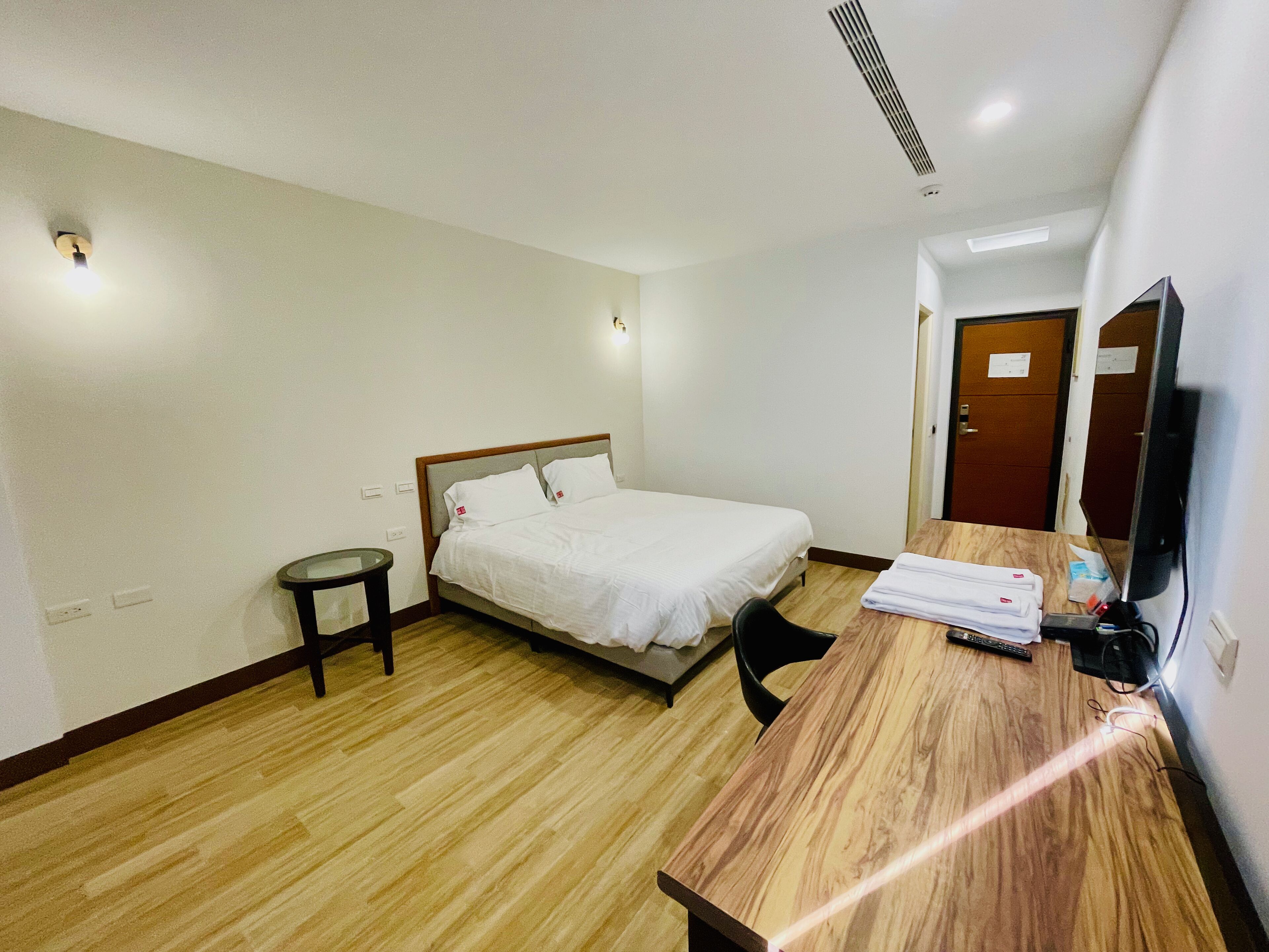 Ein Hotelzimmer mit Bett, Schreibtisch, Stuhl, Fernseher und einer Tür.