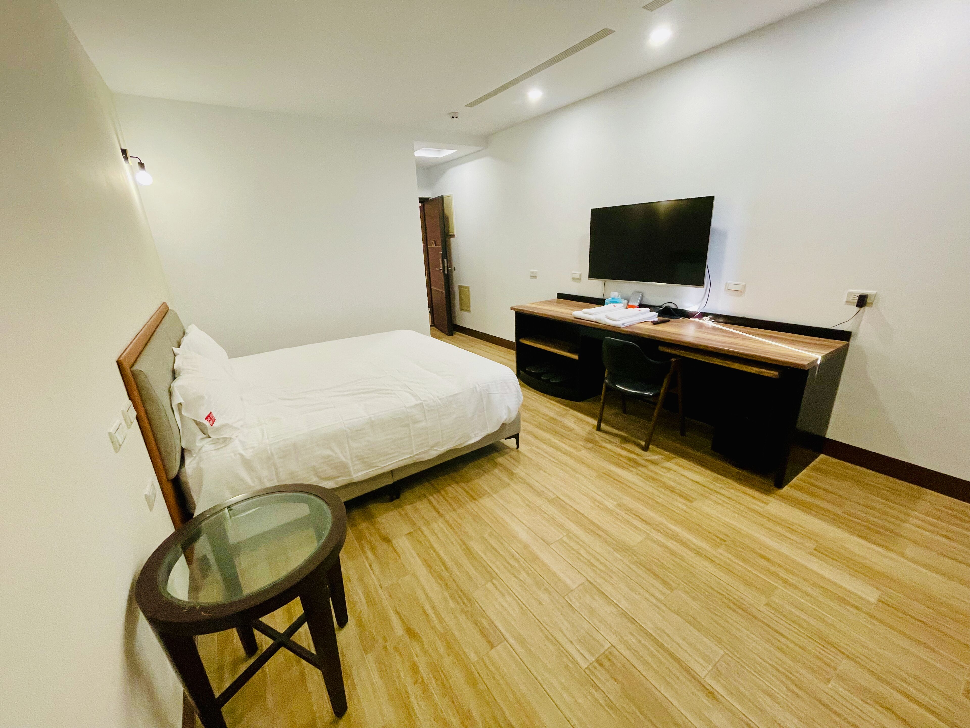 Una habitación de hotel con cama, escritorio, silla, televisor y una mesita.