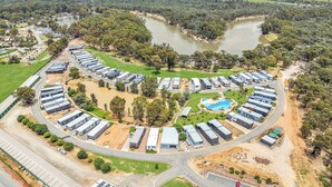 An aerial view of a campground with RVs and mobile homes arranged in a semi-circular pattern around a central swimming pool. - #56 Highview (Moama)