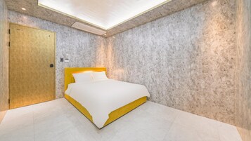 Un dormitorio moderno con una cama, una puerta de madera y una pared con textura.