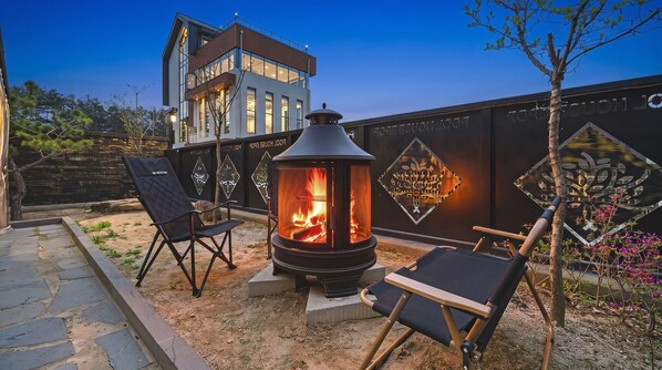 Un edificio moderno con una chimenea grande y dos sillones en primer plano.