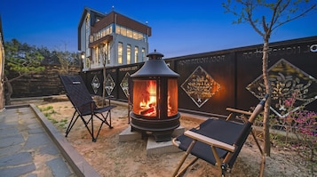Un edificio moderno con una chimenea grande y dos sillones en primer plano.