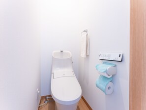 A modern toilet with a control panel, a towel hanging on a hook, and a toilet paper holder.