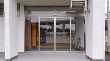 A building entrance with glass doors, a tiled floor, and a metal fence with yellow and black stripes.