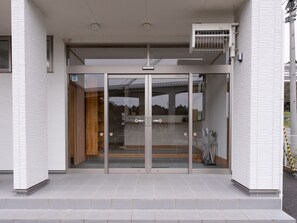 A building entrance with glass doors, a tiled floor, and a metal fence with yellow and black stripes.