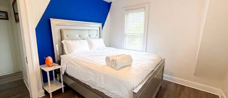 A bedroom with a bed, a nightstand, a ceiling fan, and a window with blinds.