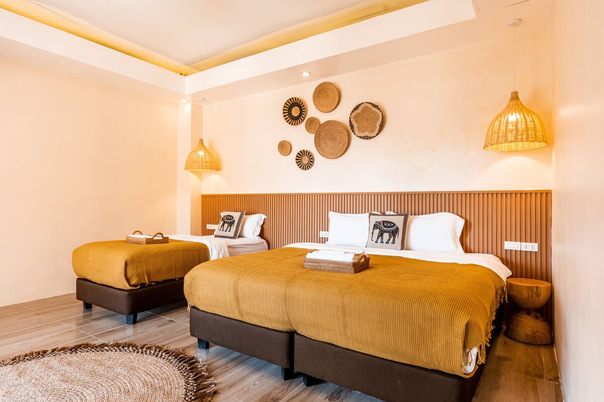 A hotel room with two beds, a wooden headboard, wall decor, and a woven rug.