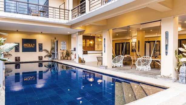 A hotel with a large indoor pool, a reception area, and a balcony with seating. - Molly Resort (Puerto Galera)
