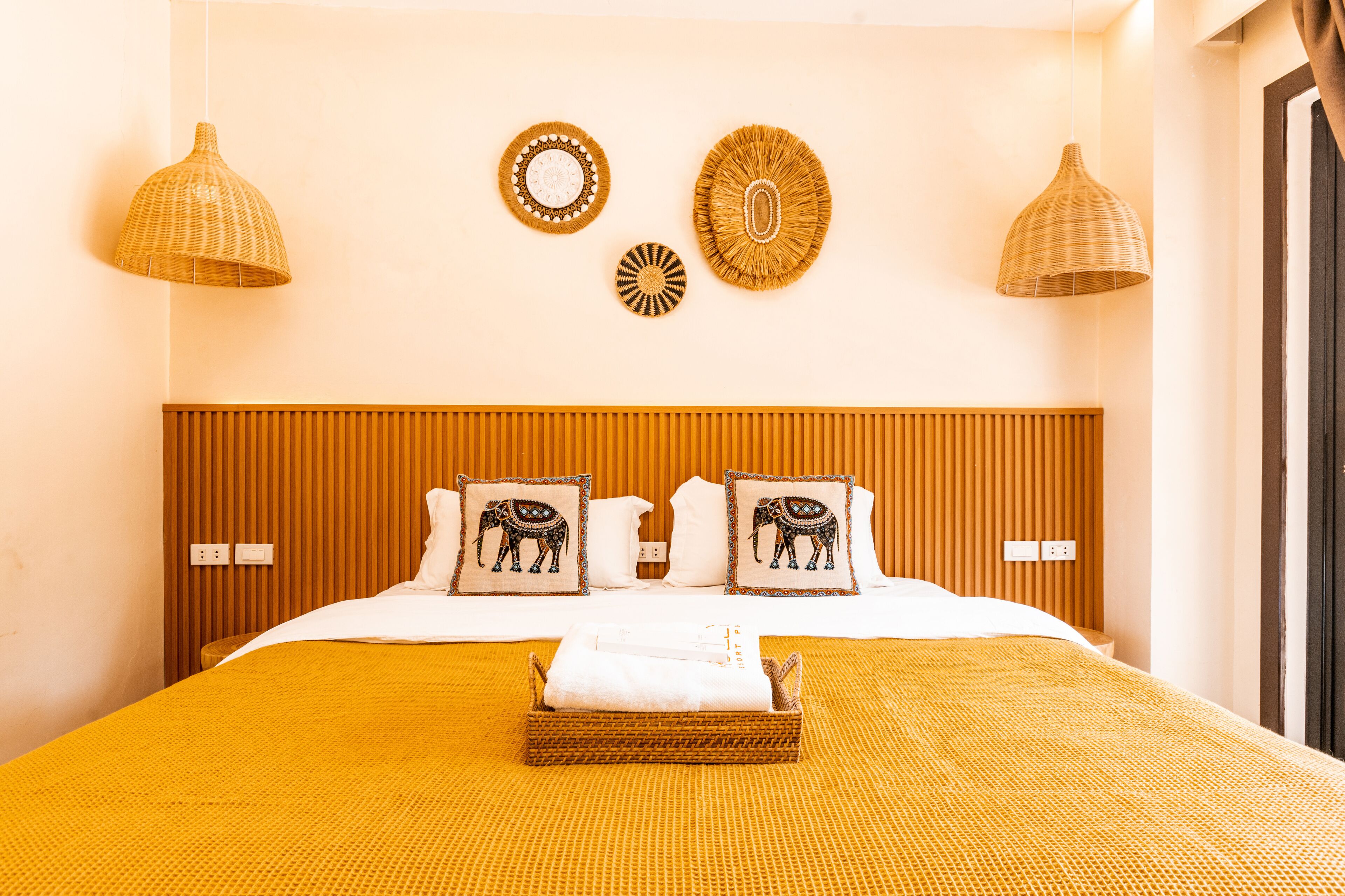 A hotel room with a bed, two wall-mounted lamps, and two decorative wall pieces.