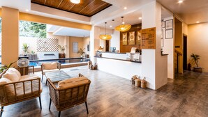 A reception area with a pool, wicker furniture, and a wooden ceiling. - Molly Resort (Puerto Galera)