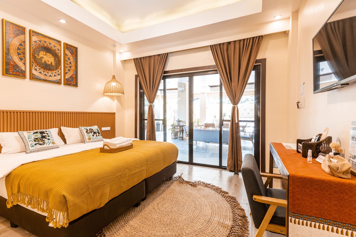 A hotel room with a large bed, a desk, and a view of the outside.
