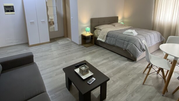 Une chambre d’hôtel moderne équipée d’un lit, d’un canapé, d’une petite table et d’un bureau avec une chaise.